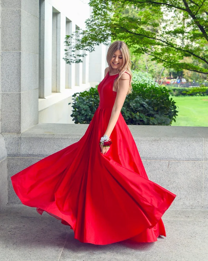 Woman twirling in a long red satin evening dress